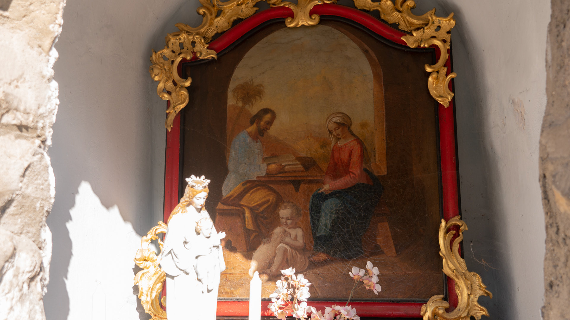 La Sainte Famille: Joseph et Marie, assis à une table, lisent un livre tandis que Jésus joue avec un agneau |  © Maurice Page 