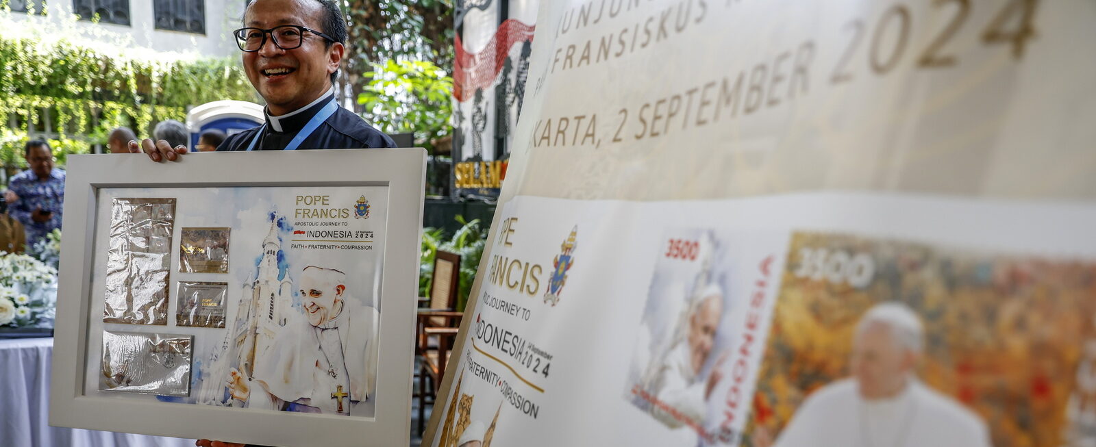 Un prêtre indonésien présente les timbres commémoratifs créés à l'occasion de la visite du pape François | © EPA/MAST IRHAM/Keystone