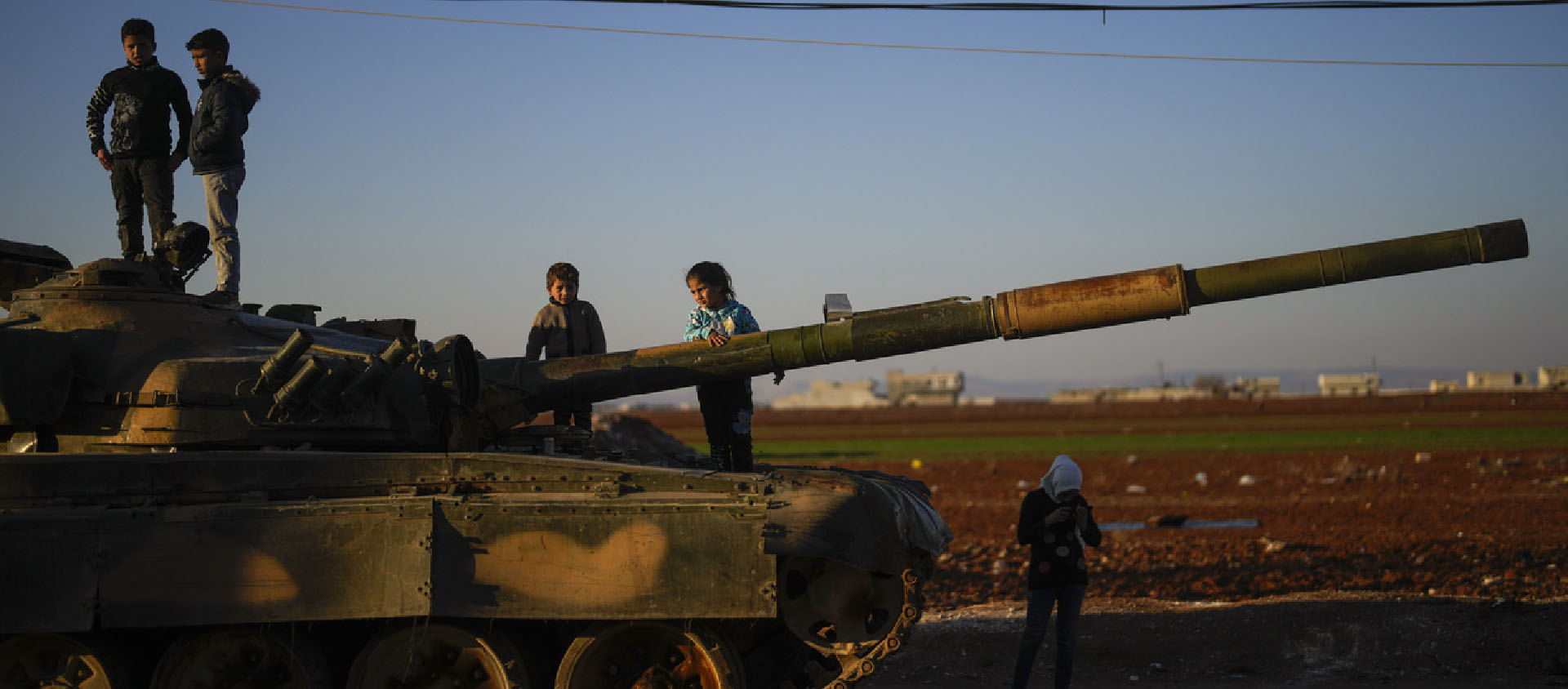 Des enfants jouent sur un char abandonné dans la banlieu d'Alep | © AP Photo/Khalil Hamra/Keystone